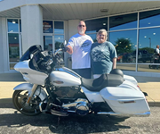 Smiling couple posing in front of motorcycle
